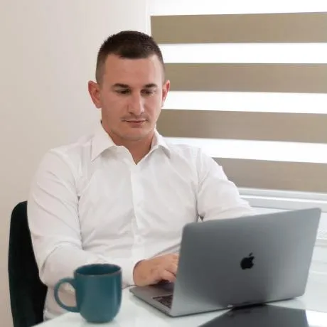 Dušan Šušić at a desk, working on a laptop